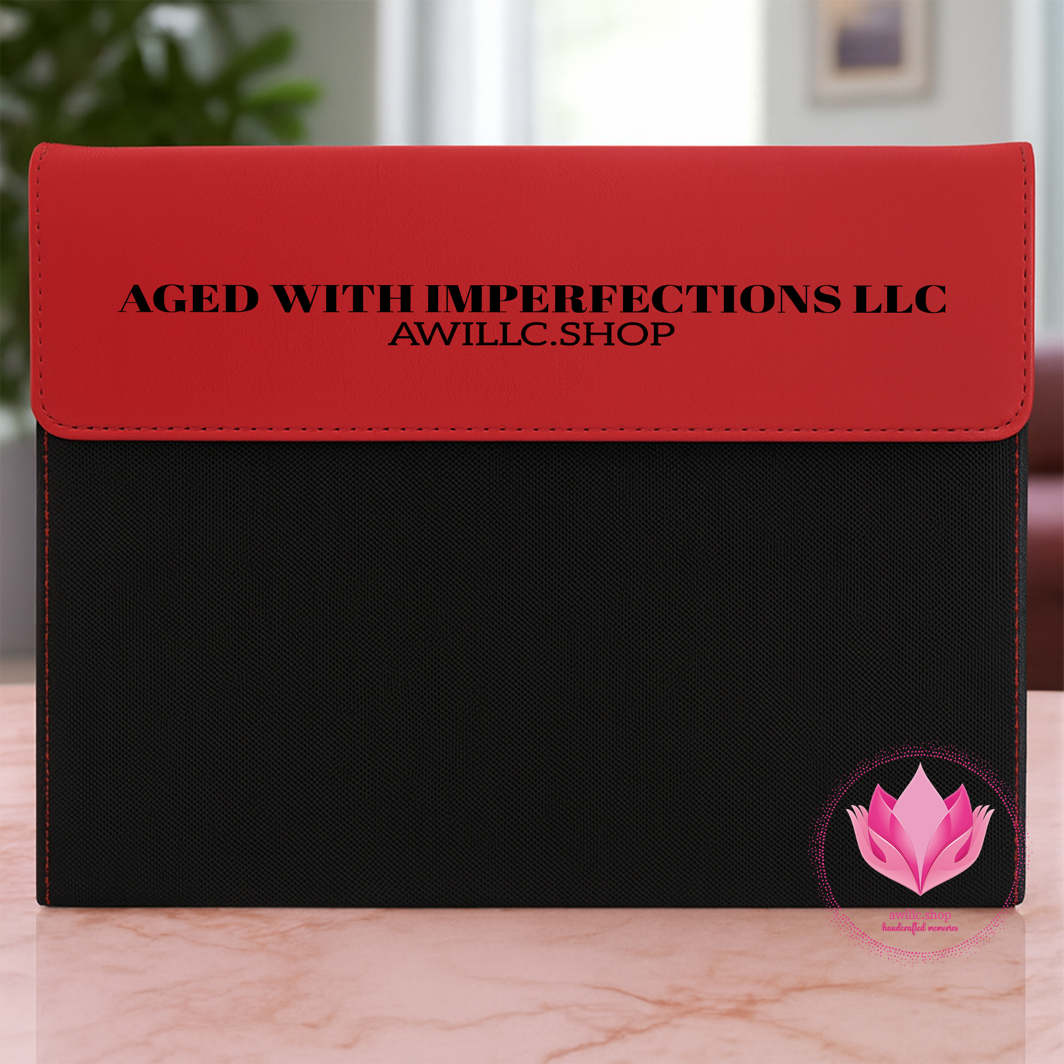 Engraved Portfolio Red and black pouch with 'Aged with Imperfections LLC' branding on a marble surface.