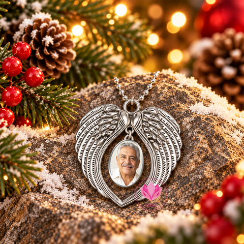 Silver-tone angel wing photo charm with a man's portrait, displayed on a snowy rock among Christmas greenery and red berries.