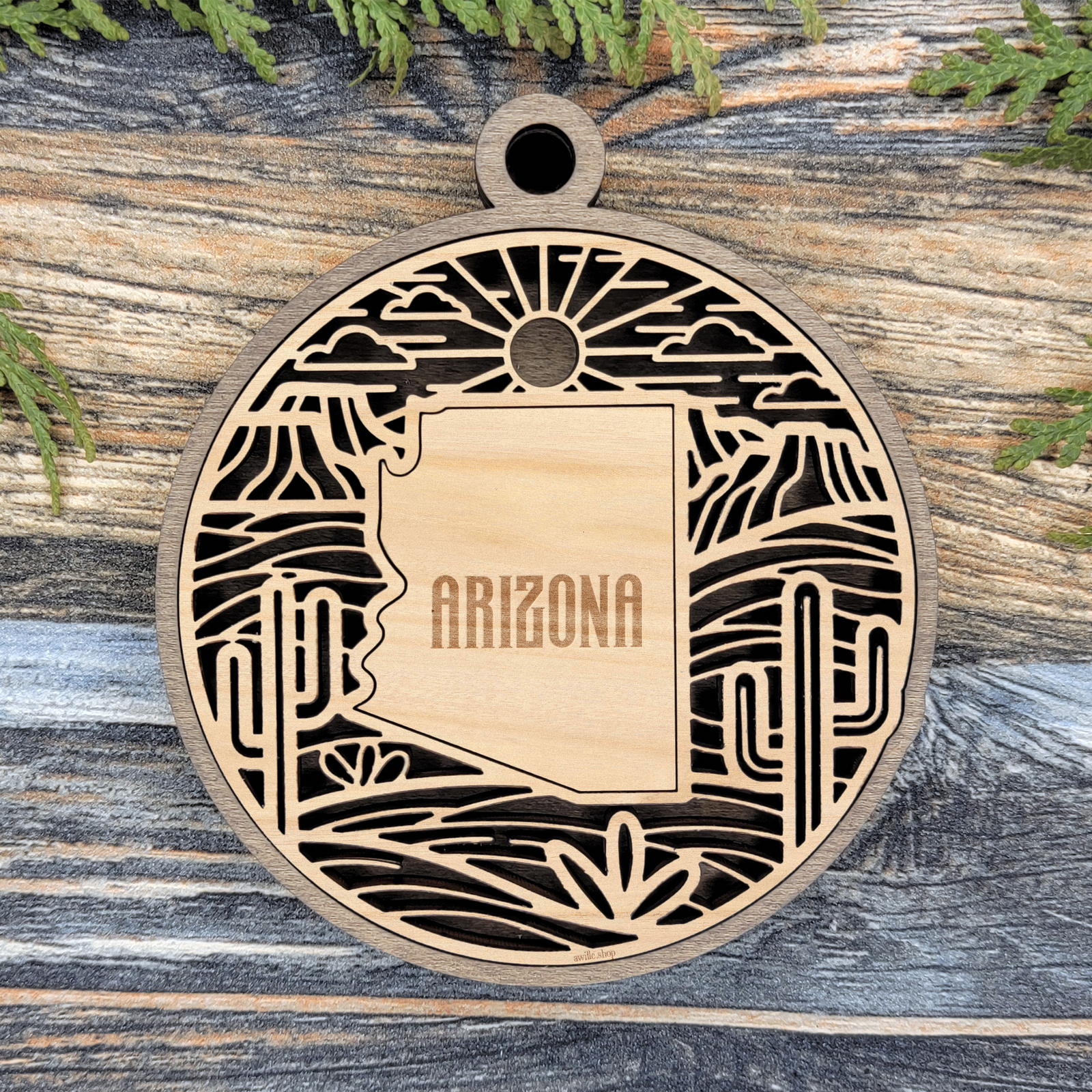 Layered Arizona wood ornament with laser cut saguaro cactus, desert sun and agave framing the engraved state shape