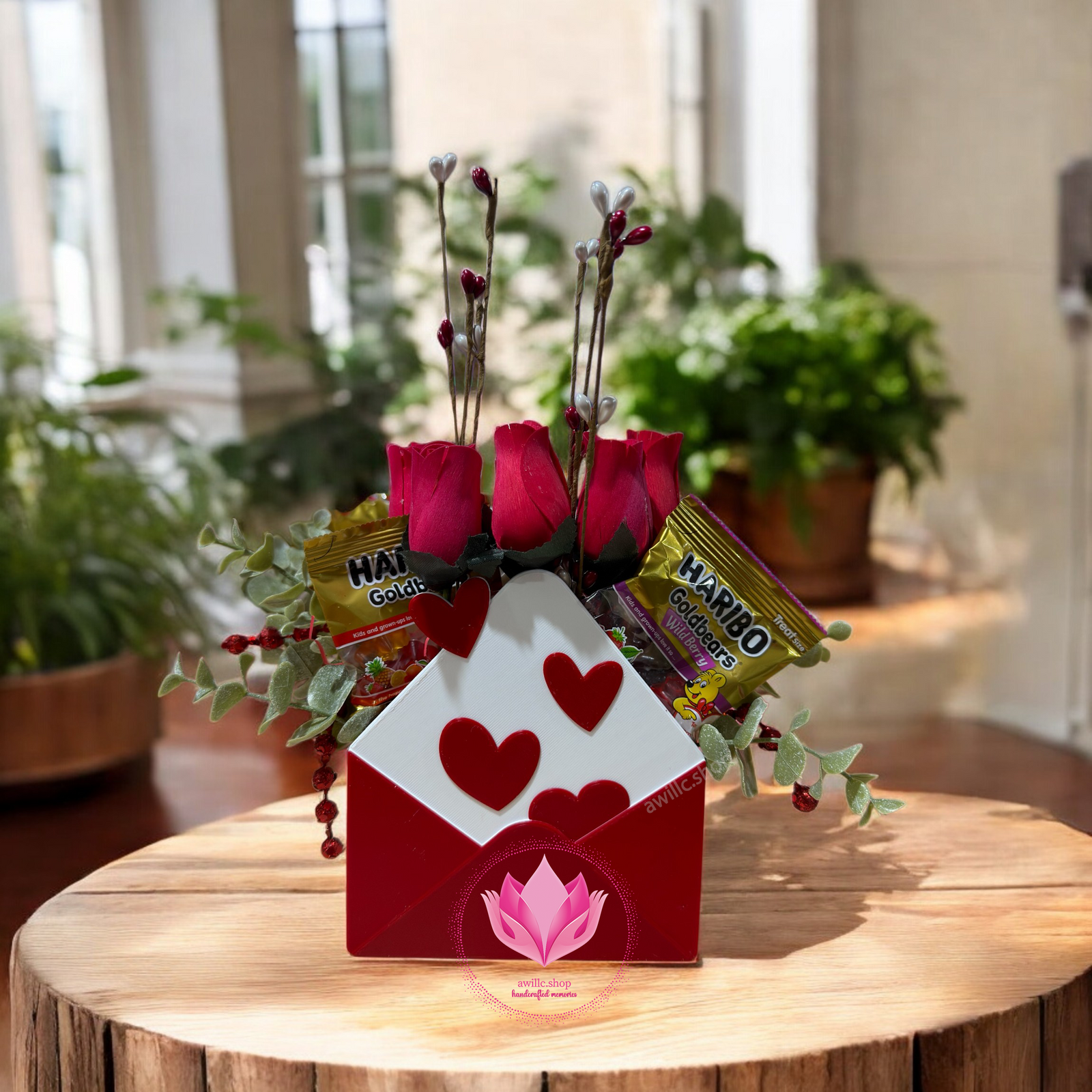 Decorative arrangement with red roses and candy in a heart-shaped box on a wooden table.