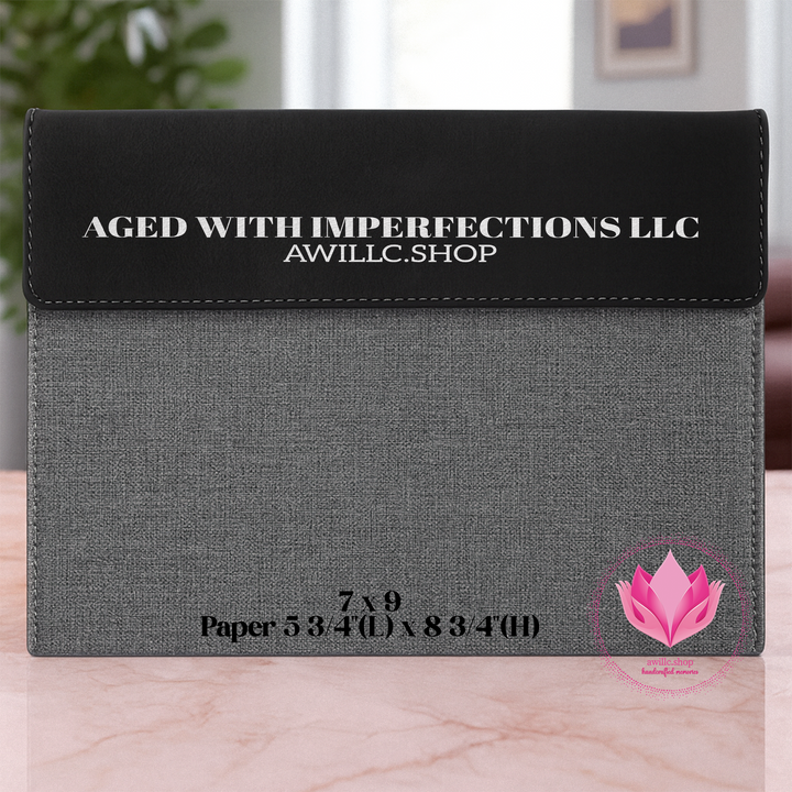 Engraved Portfolio Black and gray fabric pouch with 'Aged with Imperfections LLC' branding on a marble surface.