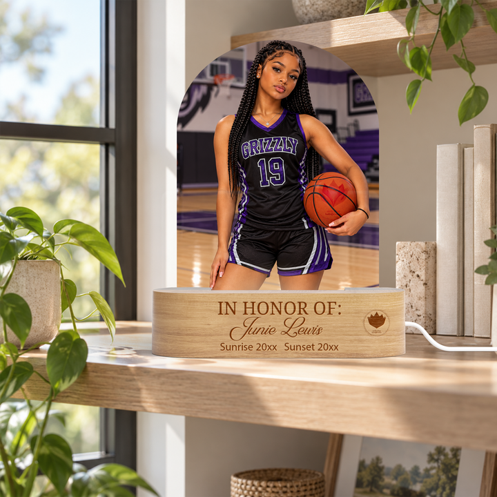 Personalized acrylic arch photo LED light with a basketball portrait and engraved wooden base, displayed on a shelf beside a window.